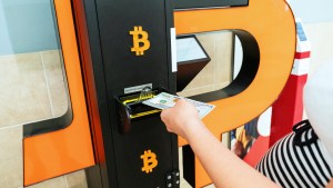 Bitcoin ATM cash teller and woman's hand withdrawing cash