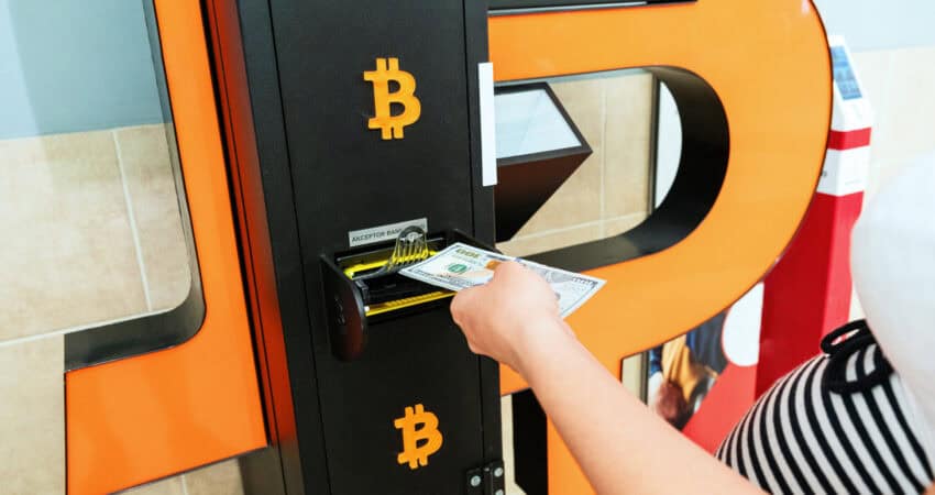 Bitcoin ATM cash teller and woman's hand withdrawing cash