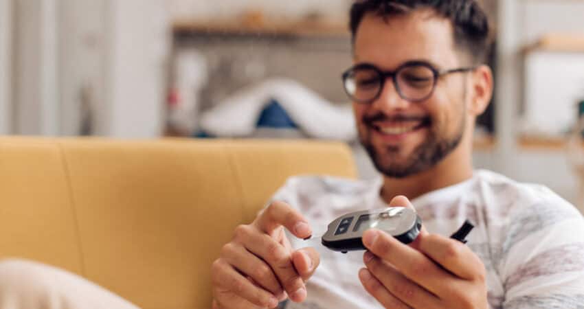 Young man measuring insulin level at home.