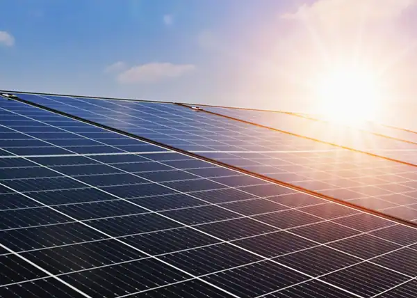 A close up image of a solar panel with the sun shining over it.