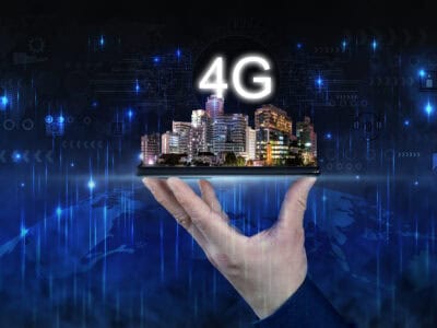 Creative background, male hand holding a phone with 4G hologram on city background. Concept of 4G network, mobile high speed internet, new generation network, mixed media.